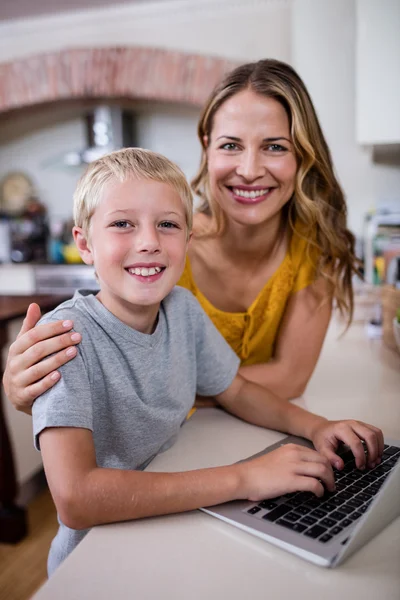 母亲和儿子在厨房中使用笔记本电脑 — 图库照片