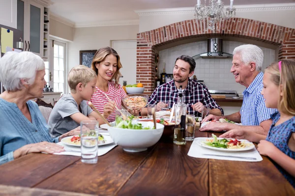 Femme servant de la nourriture à la famille dans la cuisine — Photo