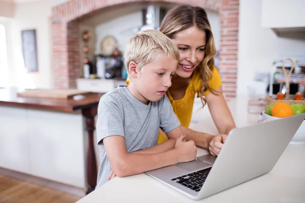 Mãe e filho usando laptop na cozinha — Fotografia de Stock