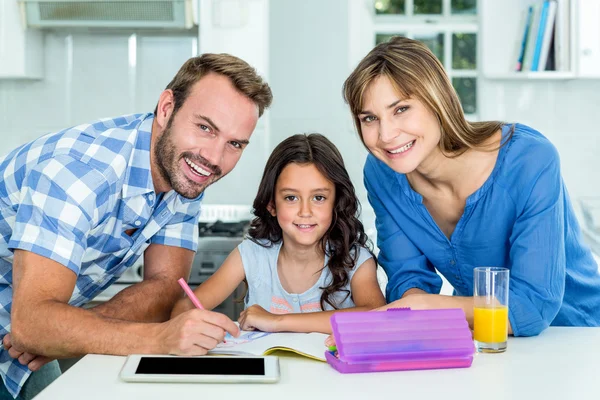 Pai e mãe assistindo filha em lição de casa — Fotografia de Stock