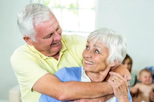 Coppia abbracciare mentre la famiglia in background — Foto Stock