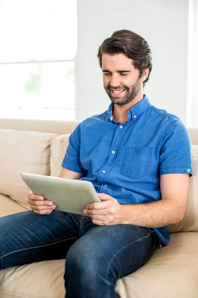 Man using digital tablet on sofa — Stock Photo, Image