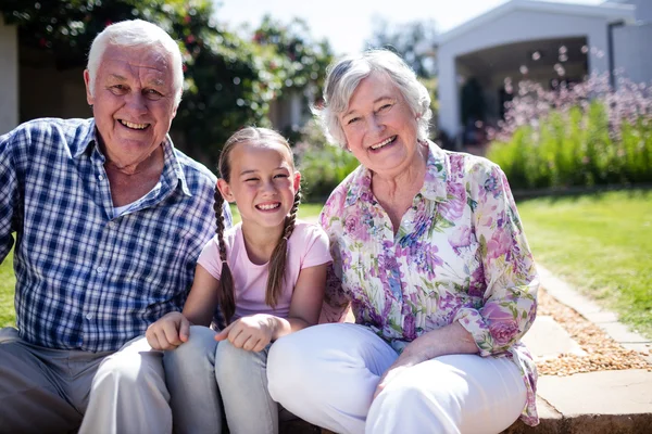 Abuelos y nieta sentados en el jardín — Foto de Stock