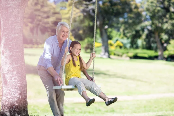 Nonno spingendo nipote su altalena — Foto Stock