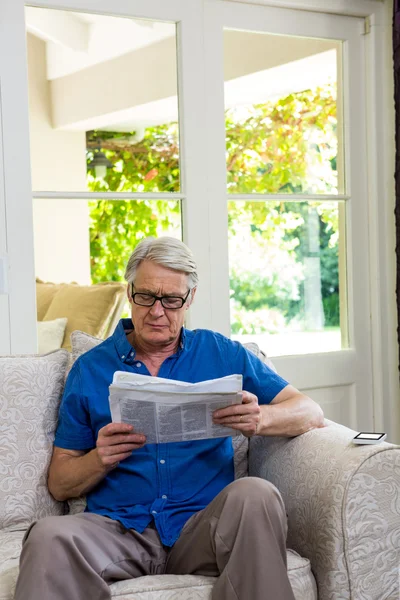 Uomo anziano che legge il giornale a casa — Foto Stock