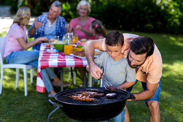 Отец учит сына готовить на барбекю — стоковое фото