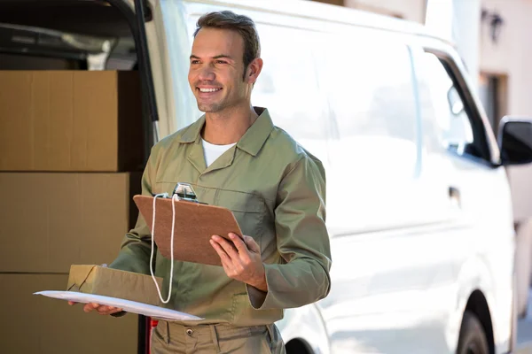 Feliz entrega hombre sosteniendo caja de cartón y portapapeles — Foto de Stock