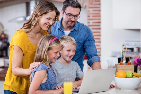 Padres e hijos usando portátil en la cocina — Foto de Stock