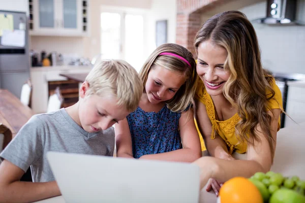 Mother and kids using laptop in kitchen — Stock Photo, Image