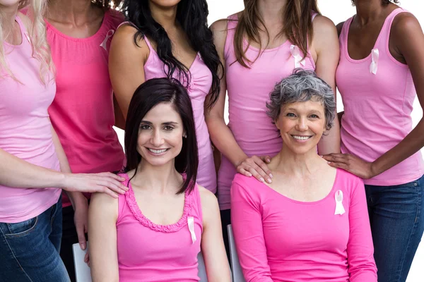 Mujeres sonrientes con trajes rosas posando para la conciencia del cáncer de mama — Foto de Stock