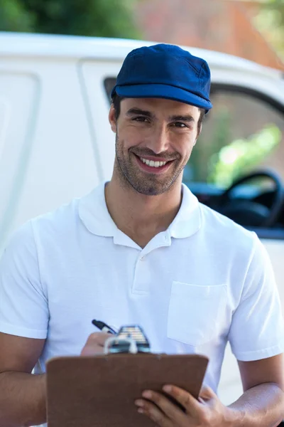 Delivery man writing in clipboard — Stock Photo, Image