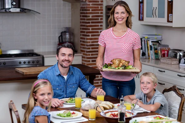 Vrouw eten serveren aan familie in keuken — Stockfoto