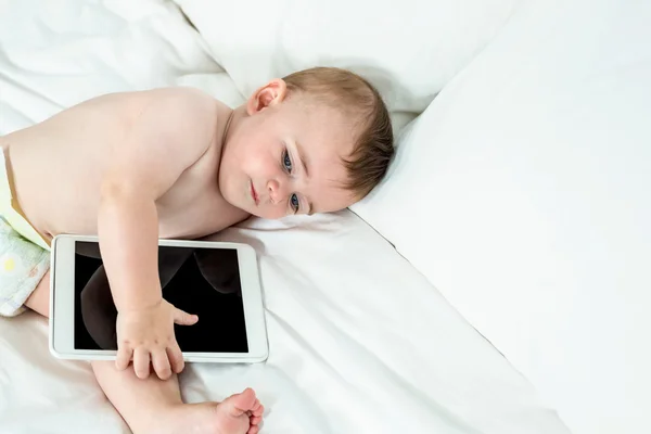 Дитячий хлопчик лежить на ліжку з планшетом — стокове фото