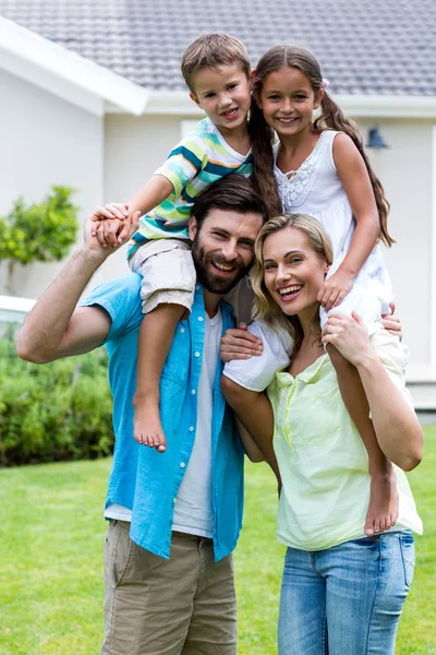 Genitori con bambini su spalle a iarda — Foto Stock