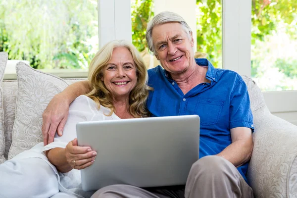 Pareja de ancianos sosteniendo la tableta sentado en casa — Foto de Stock