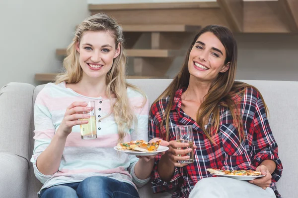 Women sitting on sofa and having pizza — Stock Photo, Image