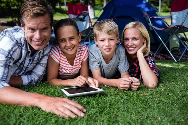 Familia acostada en la hierba y el uso de tabletas — Foto de Stock