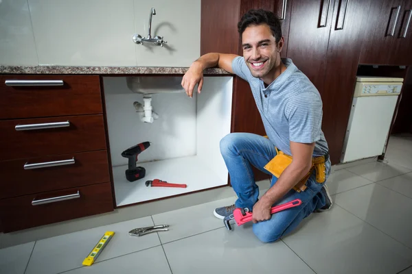 Homem sorrindo segurando chave de tubo — Fotografia de Stock