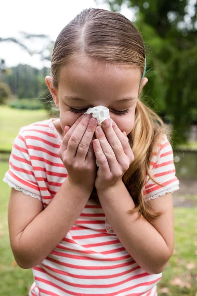Chica enferma estornudando en el parque — Foto de Stock