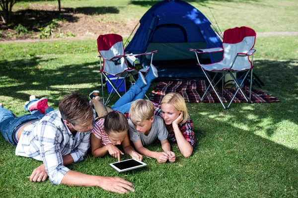 Famiglia sdraiata sull'erba e utilizzando tablet — Foto Stock