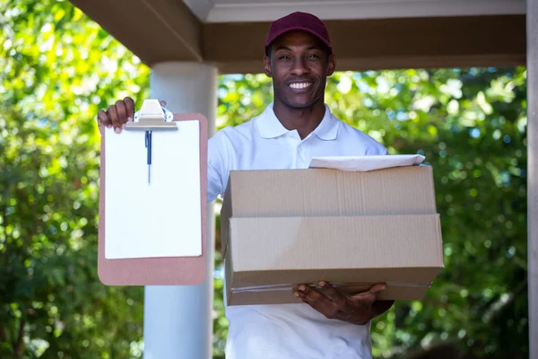 Zusteller hält Paket und Klemmbrett — Stockfoto