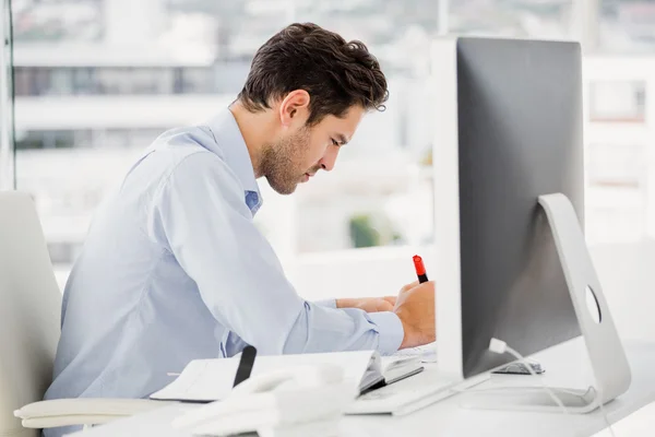 Zakenman die aantekeningen maakt op zijn Bureau — Stockfoto