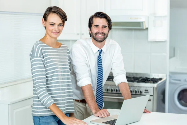 Couple with laptop standing by table — Stock Photo, Image