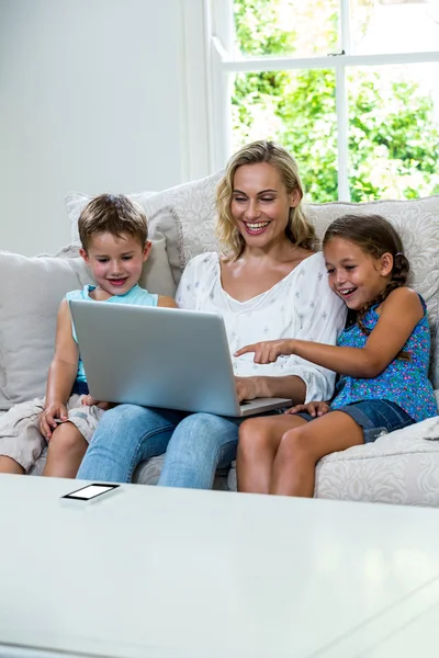 Gyermekek anyja használ laptop a kanapé — Stock Fotó