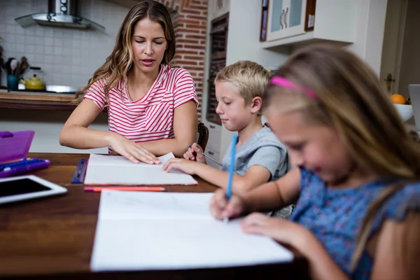 Mère aidant les enfants avec leurs devoirs — Photo