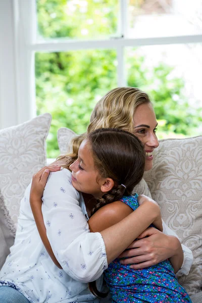 Moeder en dochter omarmen op sofa — Stockfoto