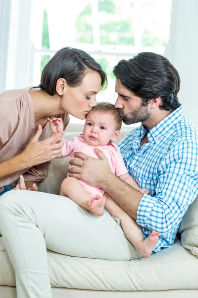 Föräldrar kissing dotter på soffa — Stockfoto