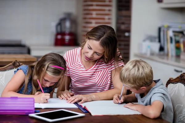 Çocuklar ev ödevlerinde yardımcı anne — Stok fotoğraf