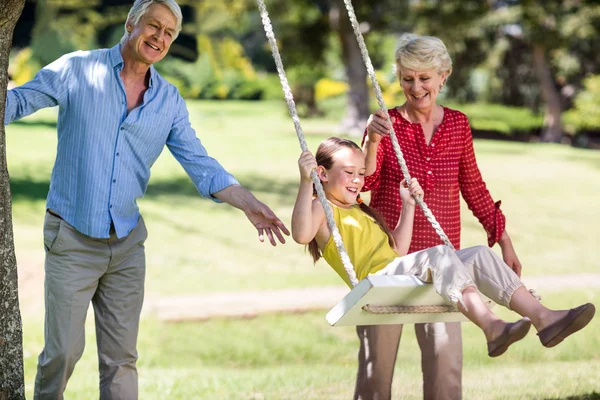 Abuelos empujando nieta en swing — Foto de Stock