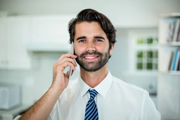 Businessman talking on cellphone in kitchen — Stock Photo, Image