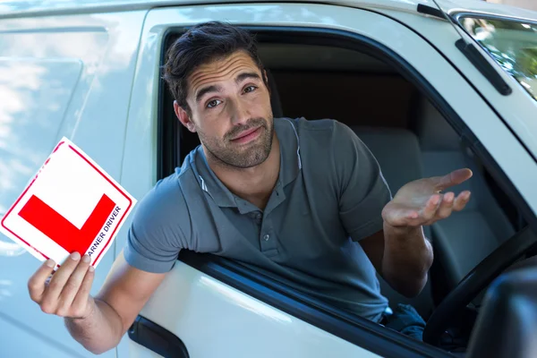 Man shrugging while holding L plate — Stock Photo, Image