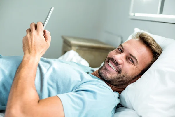 Homem usando telefone celular na cama — Fotografia de Stock