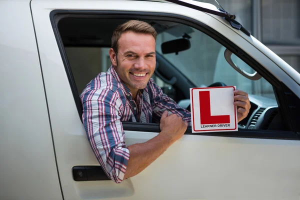 Мужчина, держащий в руках знак ученика водителя — стоковое фото
