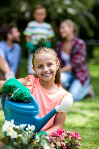 用喷壶在院子里的小女孩微笑着 — 图库照片
