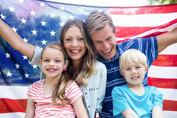 Familia sosteniendo bandera americana en parque Fotos de stock libres de derechos