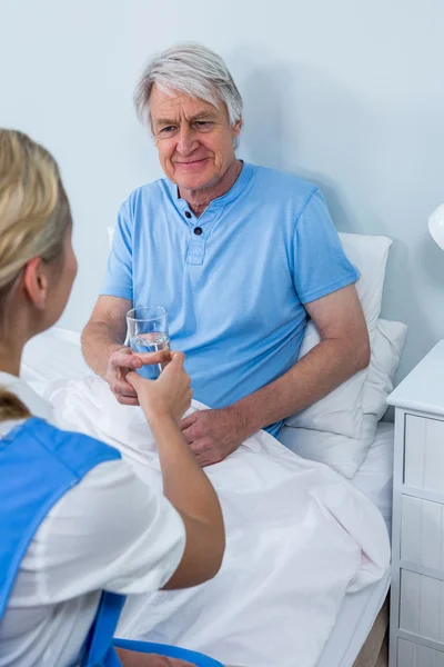 Enfermeira que dá medicamentos ao idoso — Fotografia de Stock