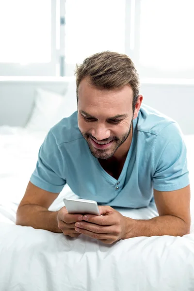 Man using cellphone while lying on bed — Stock Photo, Image