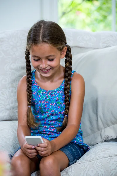 Dívka, používání mobilního telefonu na pohovce — Stock fotografie