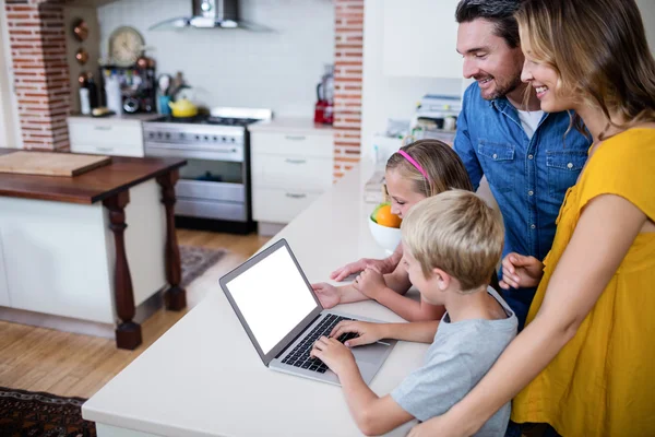 Föräldrar och barn med laptop i köket — Stockfoto