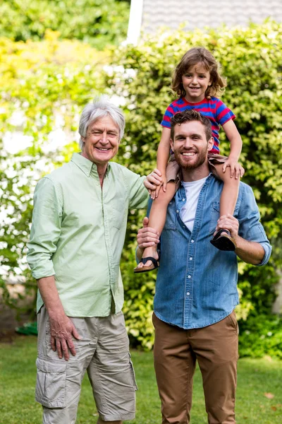 Grandfather standing with son carrying grandson — Stock Photo, Image