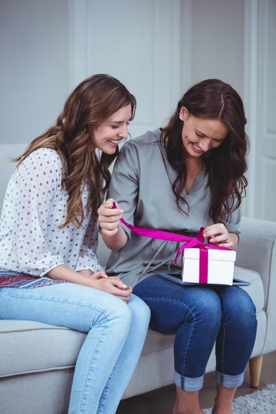 Friends unwrapping gift in living room — Stock Photo, Image