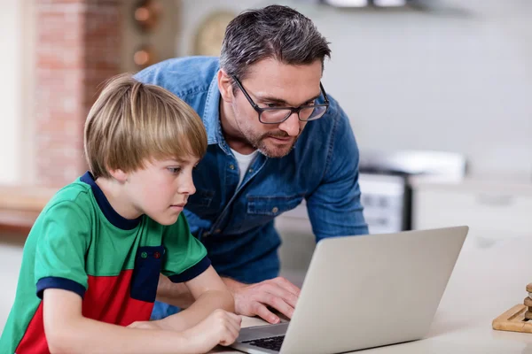 Pai e filho usando laptop na cozinha — Fotografia de Stock