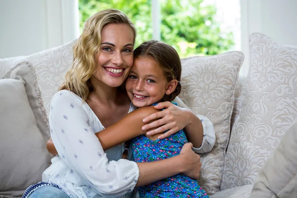 Mother and daughter embracing on sofa — Stock Photo, Image