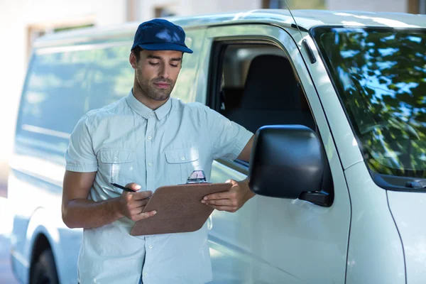 Delivery person looking at clipboard — Stock Photo, Image
