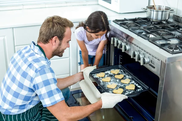 Father placing cookies in oven — Stock Photo, Image