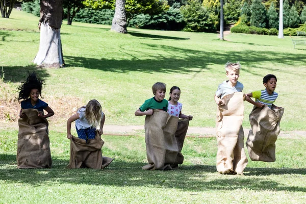 Enfants ayant une course en sac dans le parc — Photo